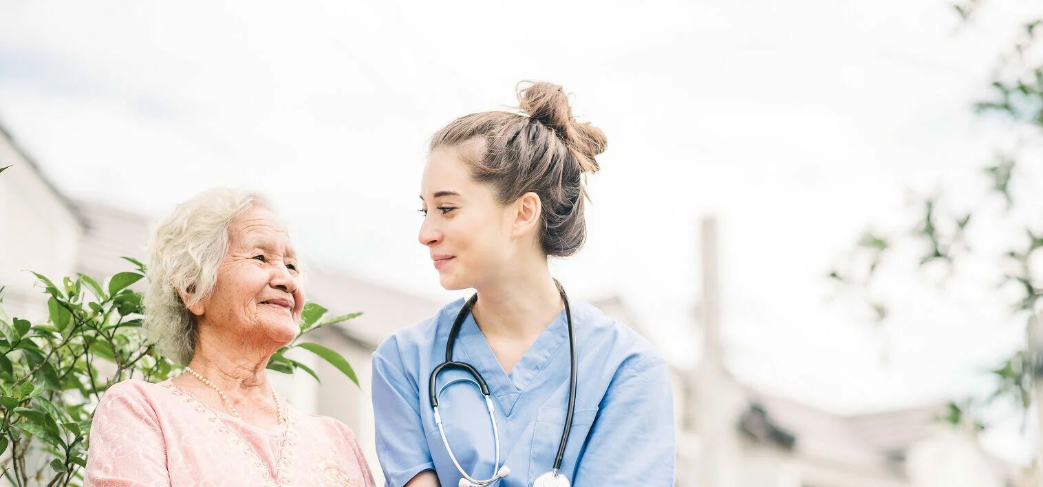 Smiling nurse caregiver holding hand of happy Asian elderly woman outdoor in the park 2022/03/AdobeStock_265162640-1-e1647895501831.jpeg 