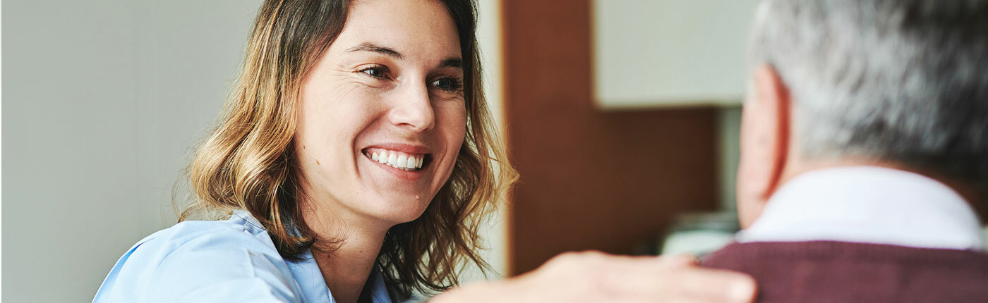 white woman smiling holding shoulder of elderly man