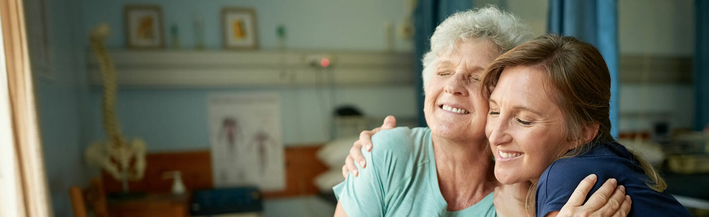 elderly mother and daughter embracing and smiling