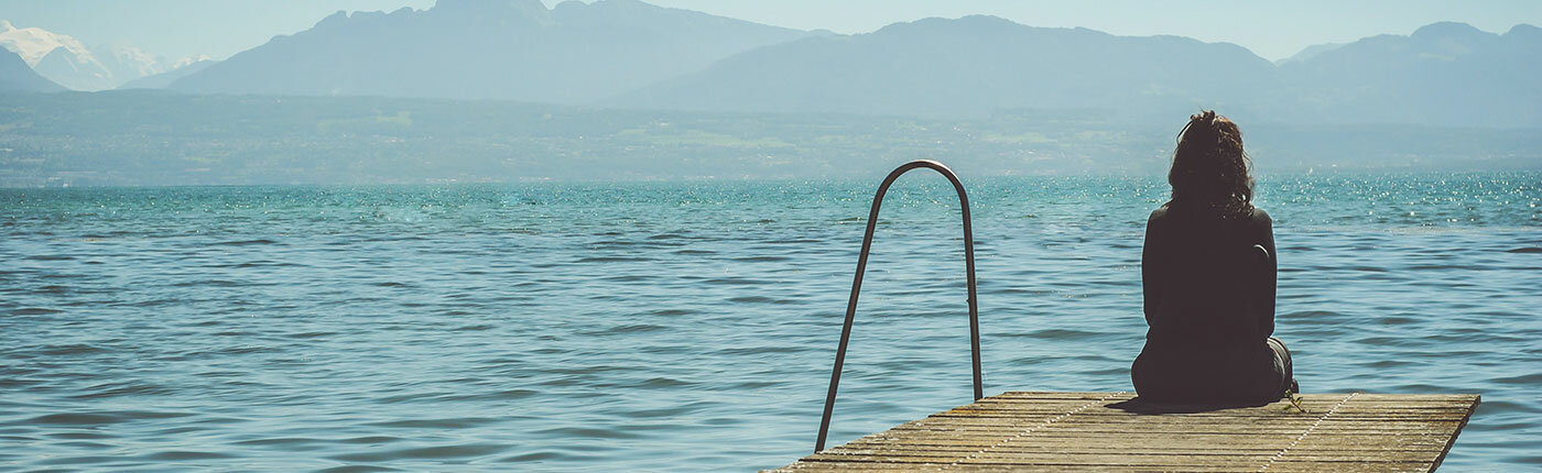 woman alone on pier looking out at the waves