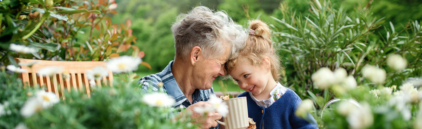 elderly white grandma snuggling with granddaughter in the garden