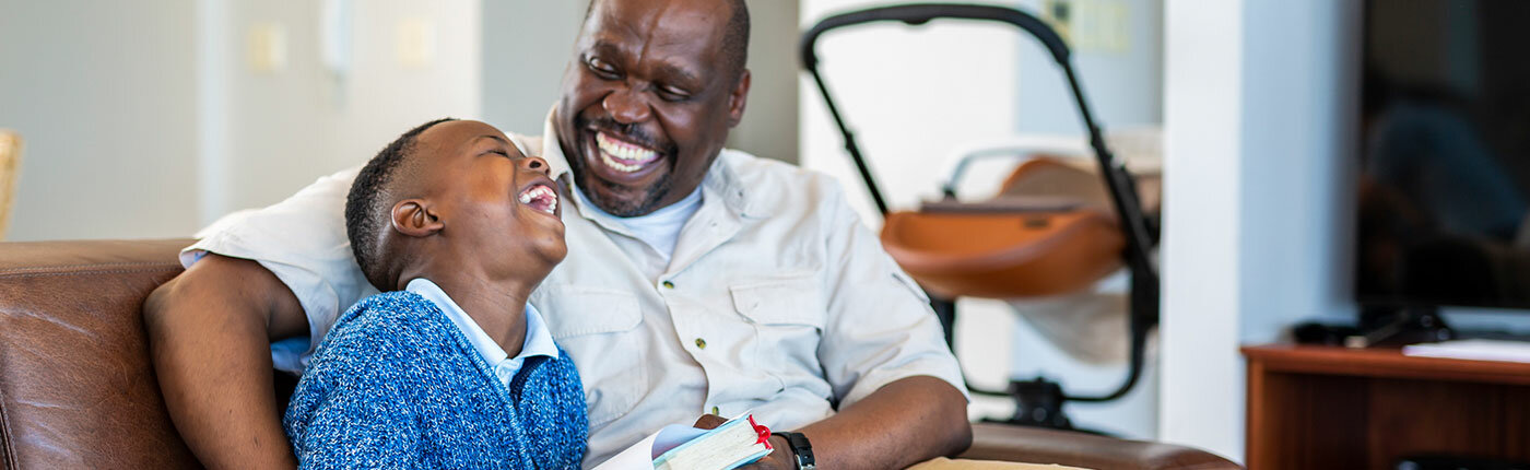 african american grandfather reading and laughing with grandson