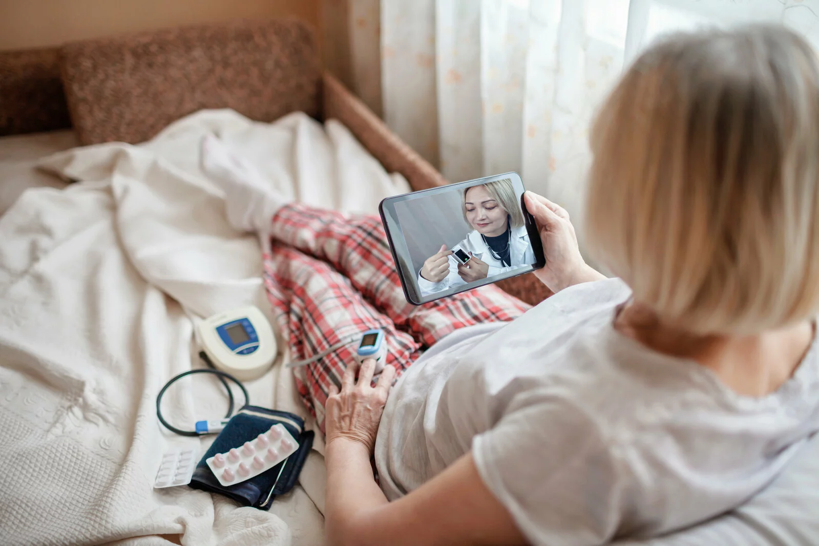 Old woman in bed looking at screen of laptop and consulting with a doctor online at home, telehealth services during lockdown, distant video call, modern tech healthcare application 2022/11/AdobeStock_404249343.jpeg 